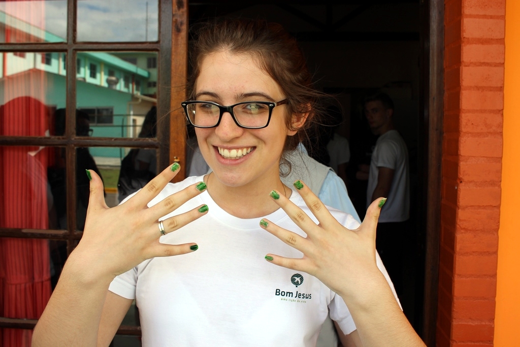 Estudante exibe as unhas pintadas por moradora do Pequeno Cotolengo.